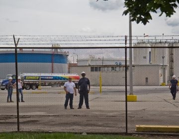 Refinery works watch protestors outside the PES refinery Tuesday. (Kimberly Paynter/WHYY)