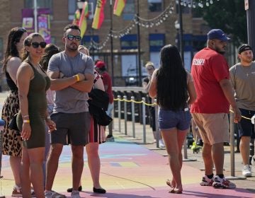 People, some with masks and some without, wait in line to be seated outdoors on a pier