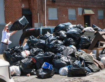 a resident throws trash into an overflowing dumpster